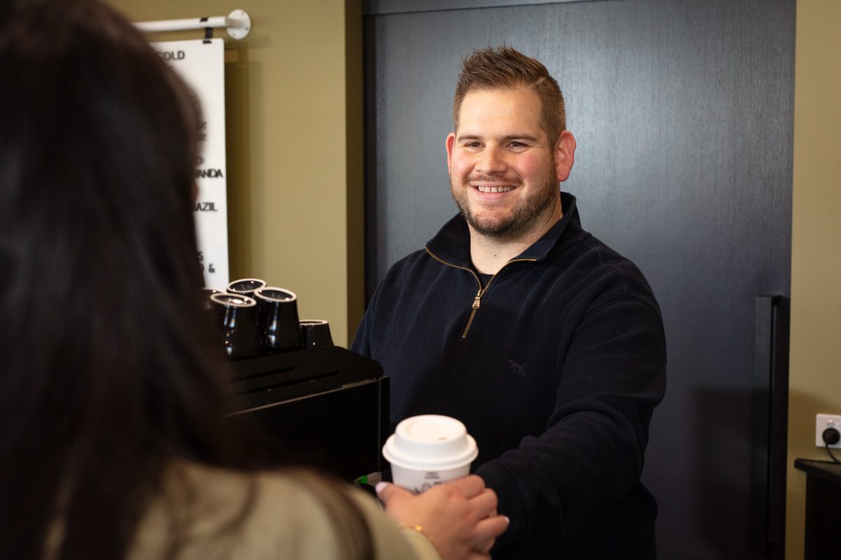 Caleb Evans serves a customer a takeaway coffee