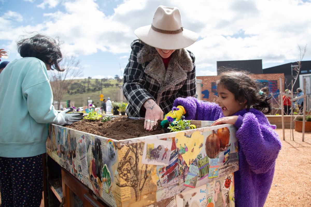 woman showing young girl how to plant flowers