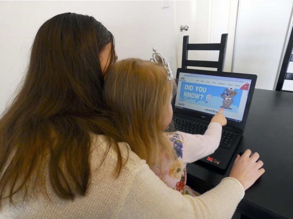 Mother and daughter pointing towards computer