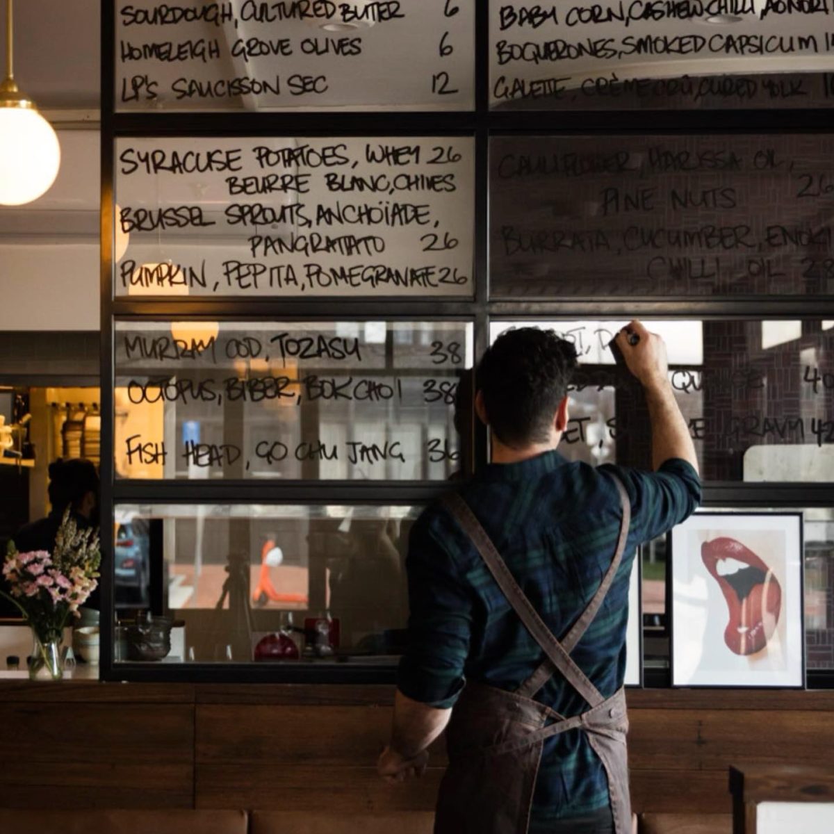 Louis writes in black pen on glass menu