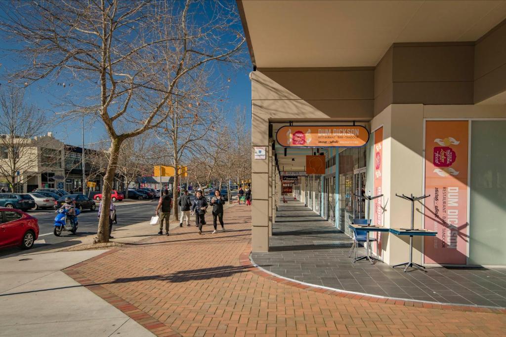 The corner of Cape and Challis street with Dum Dickson on the right, people walking along the footpath to the left. 