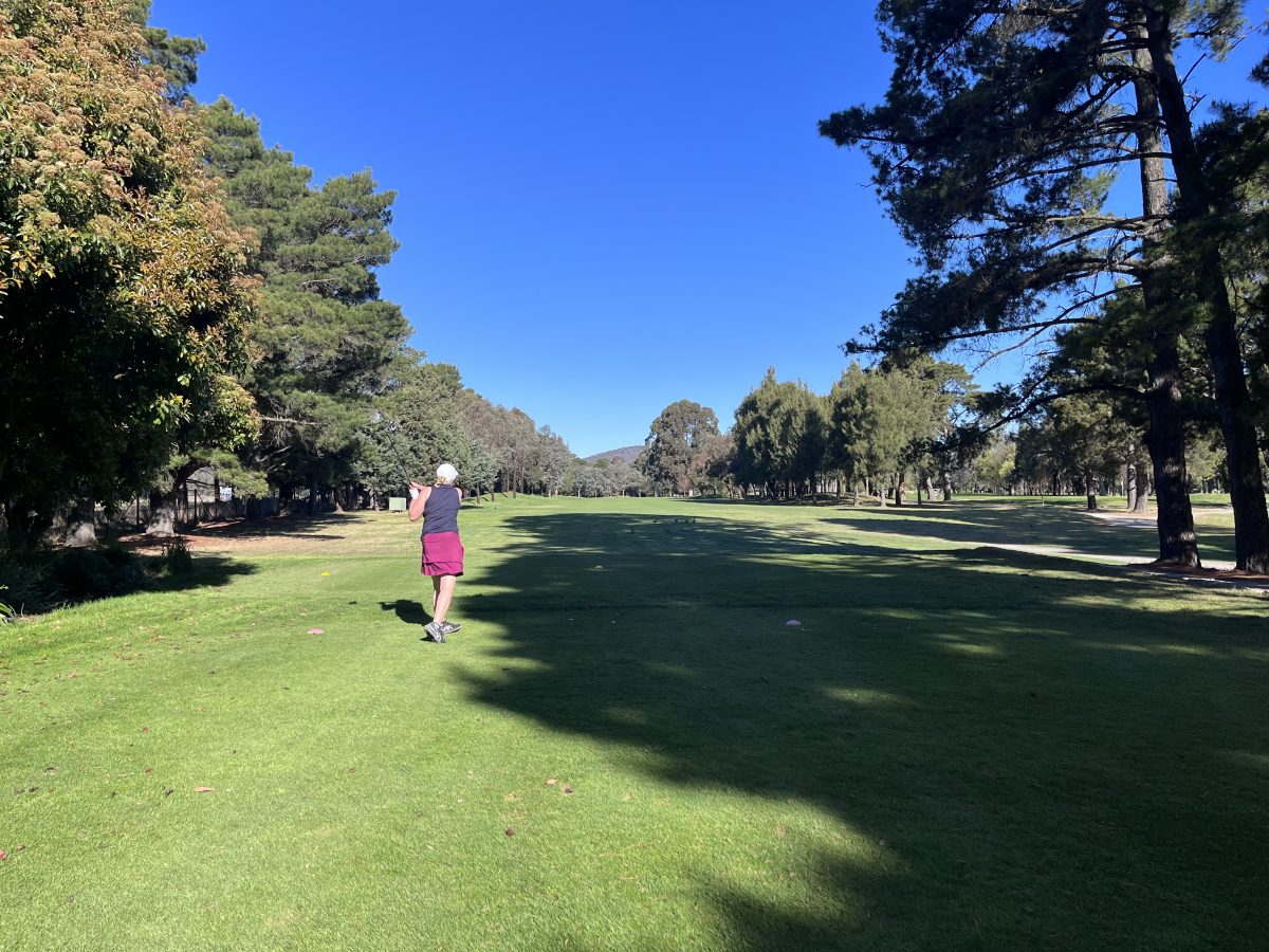 woman hits a golf ball off the tee