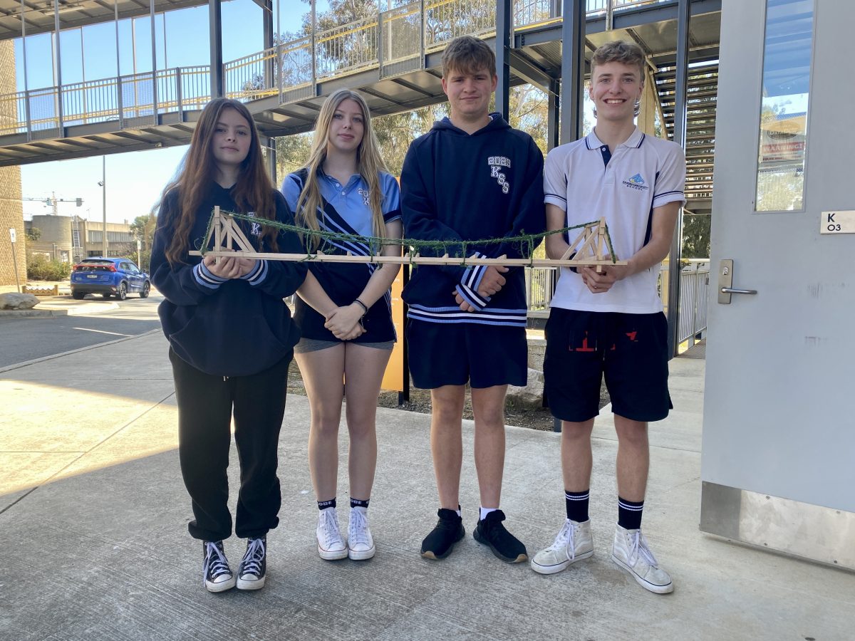 four students holding a model bridge