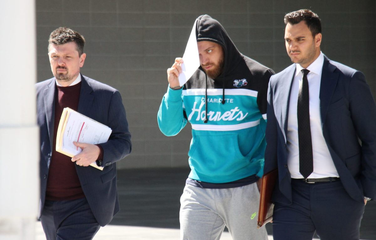 man in hoodie leaves court flanked by two lawyers