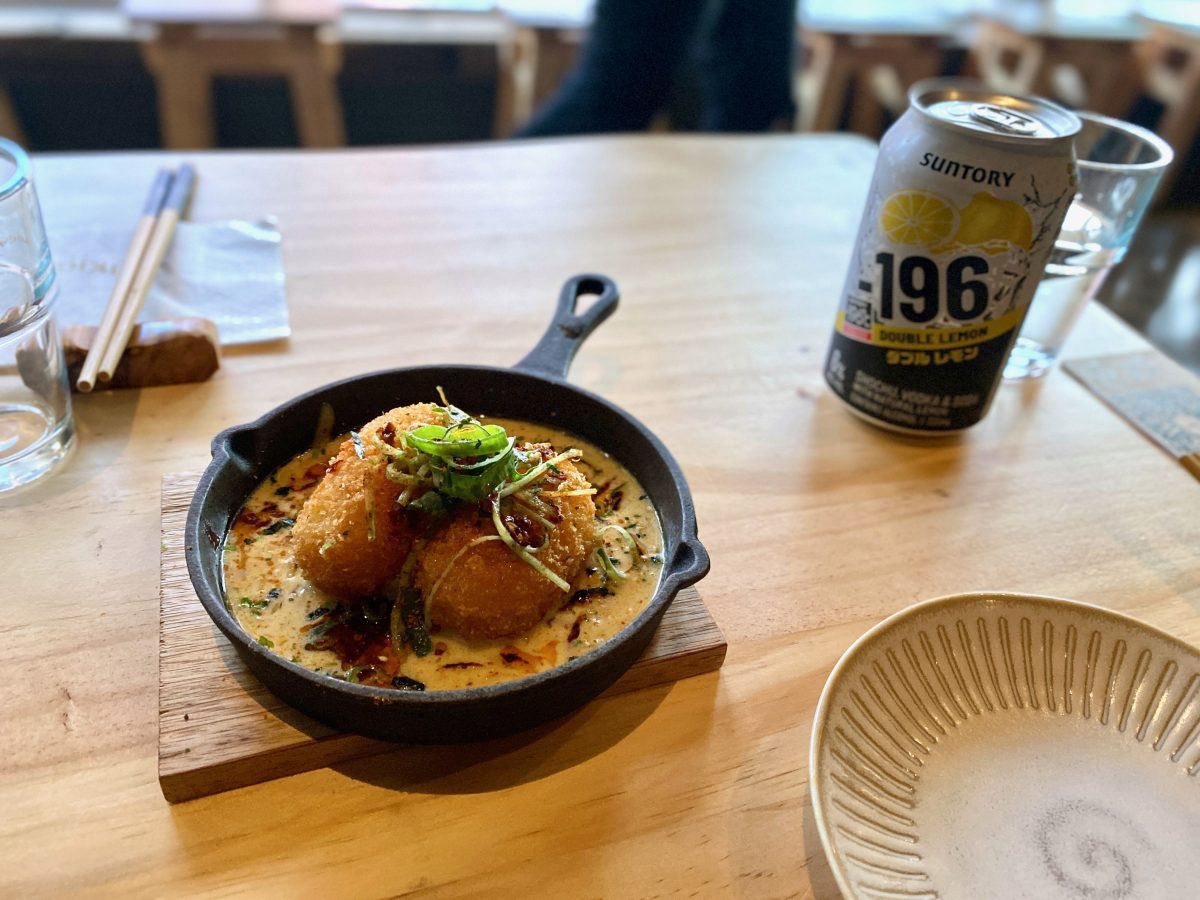 Small cast-iron dish with two croquettes topped with spring onion