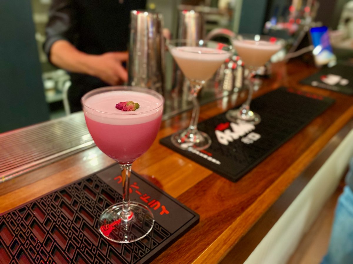 Small pink cocktail topped with a dried rosebud.