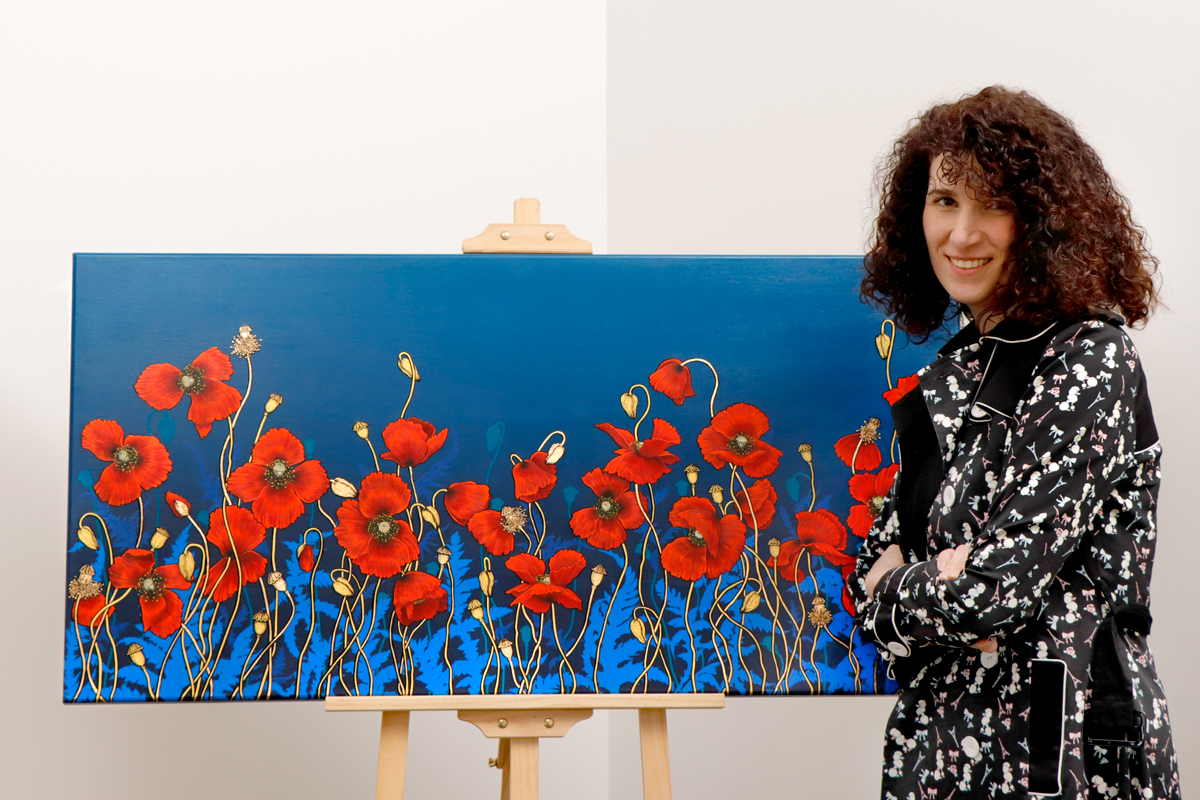 Canberra artist Adriana Seserko in front of her artwork of red poppies on a blue background