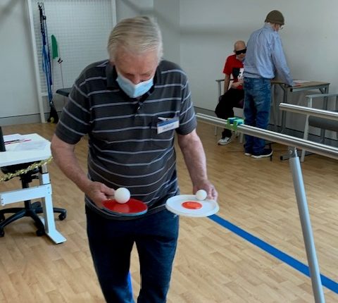 Patient balancing ping pong balls on ping pong paddles and walking