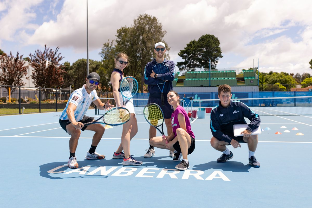 People posing with tennis racquets on a tennis court