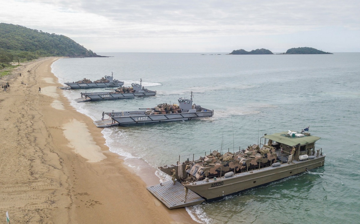 four landing craft unloading vehicles and personnel.