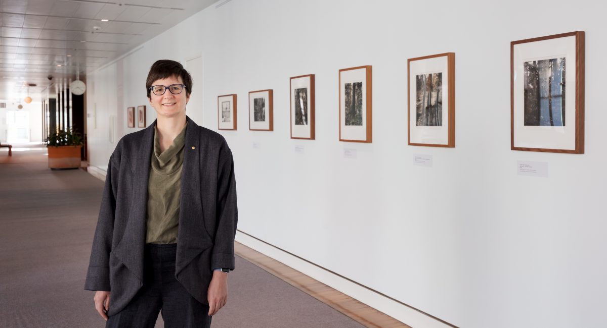 Penelope Grist OAM in front of framed images