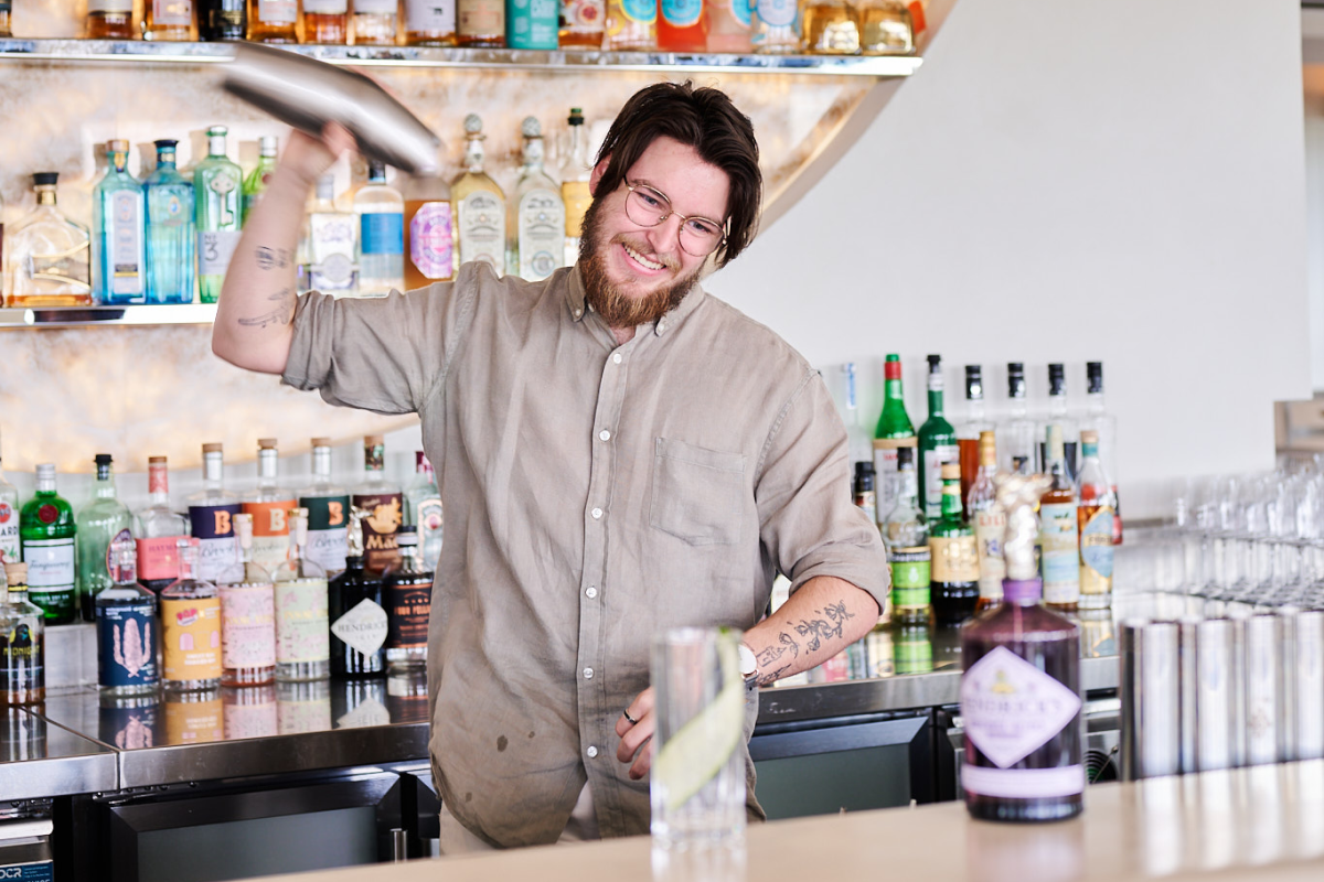 Josh Miller shaking a cocktail shaker behind the bar at Leyla