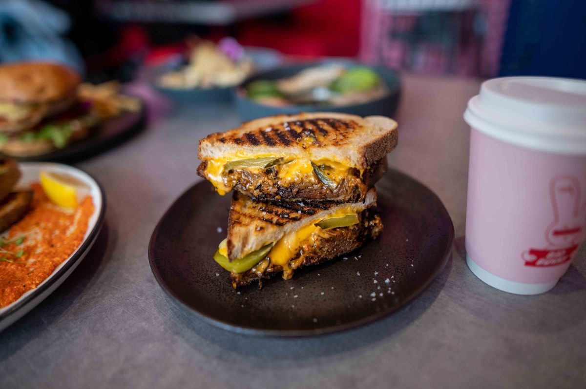 A toasted sandwich on a table of food.