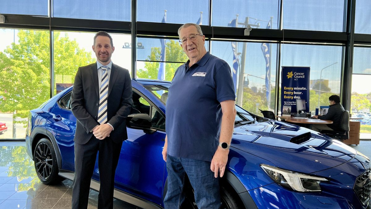 twom men standing next to a car in a showroom