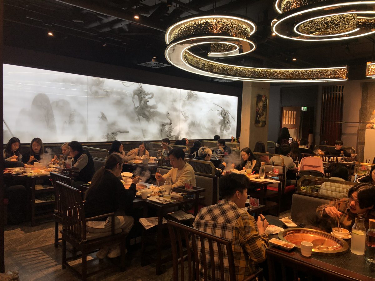 A full room of diners in a hotpot restaurant at night