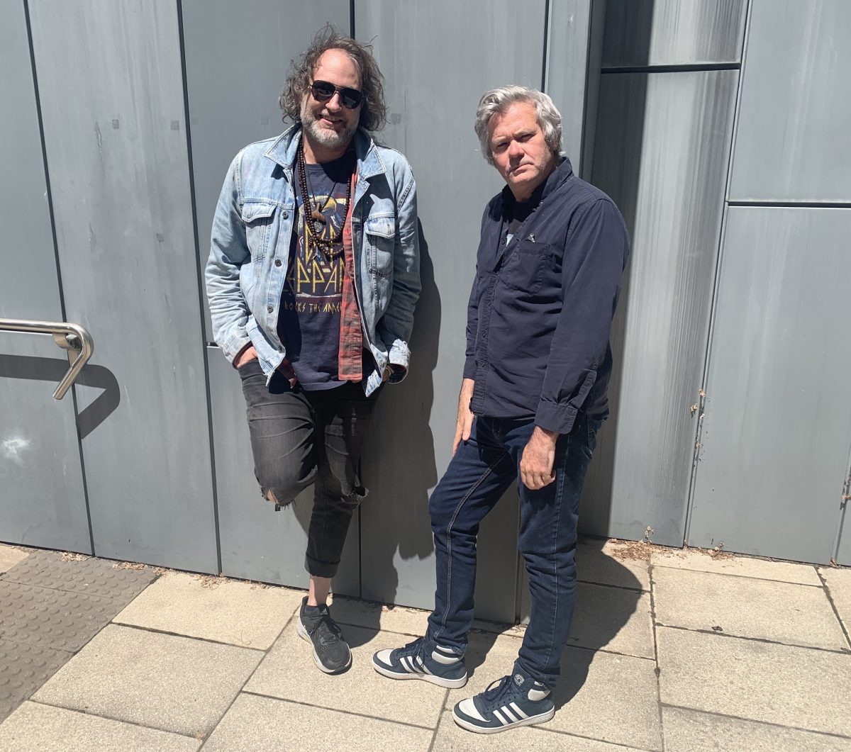 Glenn (left) and Paul (right) standing next to each other while leaning against a wall outside the Canberra Theatre Centre.