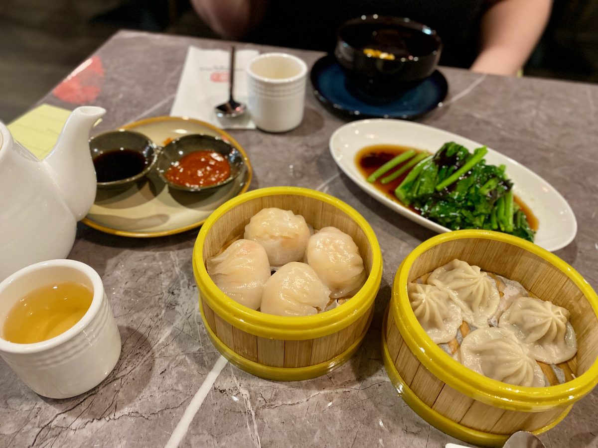 Two steamer baskets with dumplings and a dish of greens.