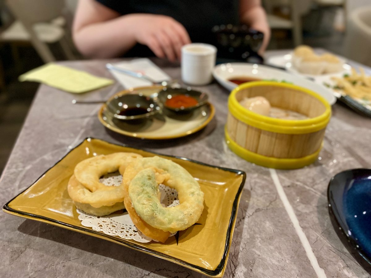 Two fried circles of dough and a steamer with dumplings on a table