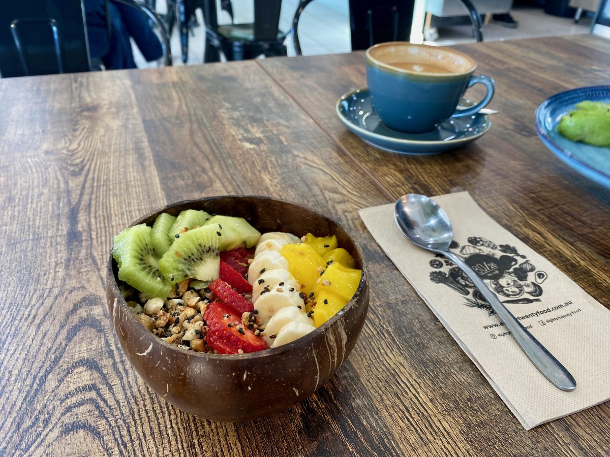 Half coconut bowl with colourful fruits scattered with seeds and nuts