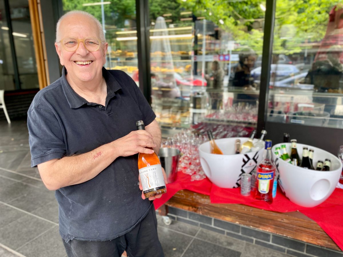 Tony smiles and holds a bottle of Sapling Yard wine.