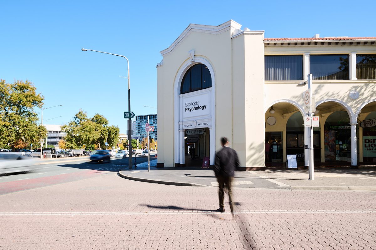 Blurred figure crosses the street towards Strategic Psychology in Canberra