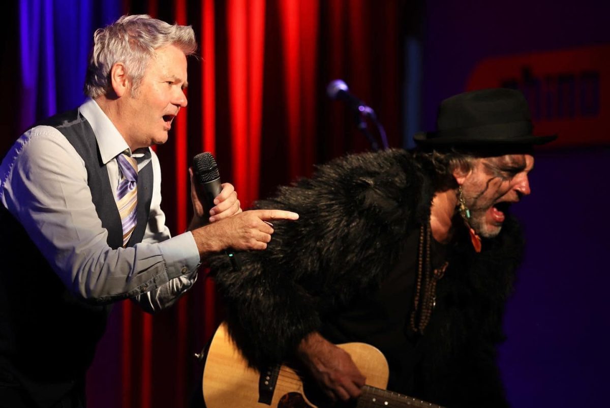 Paul (left) singing and Glenn (right) playing guitar on stage.