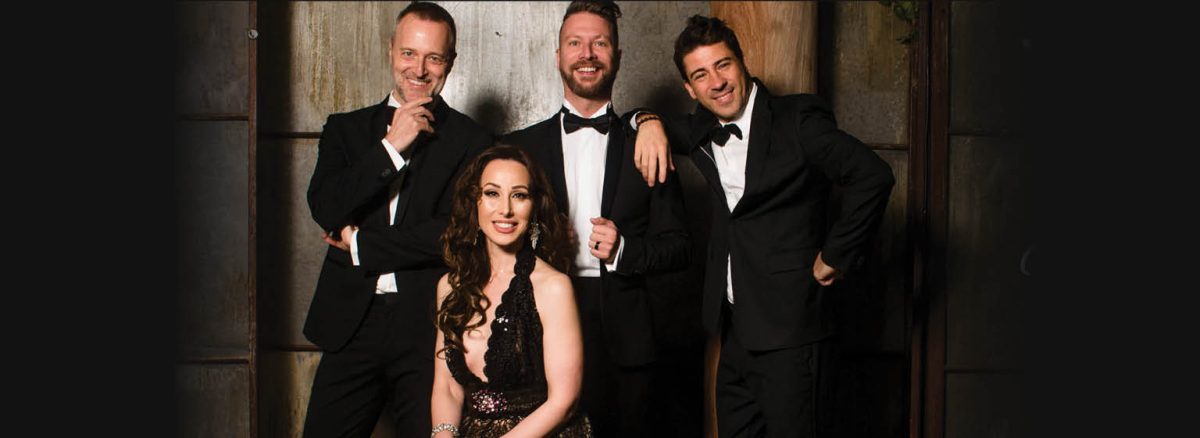 Three men in black suits and bowties behind a seated woman in a black dress