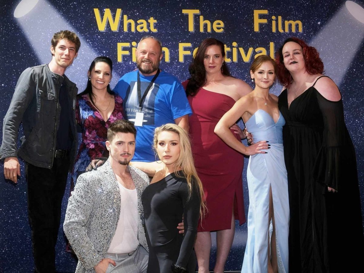 award recipients and attendees posing in front of What The Film Film Festival backdrop