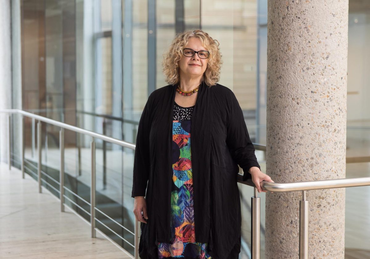 natalie wilson standing next to a rail wearing a black cardigan over a colourful dress