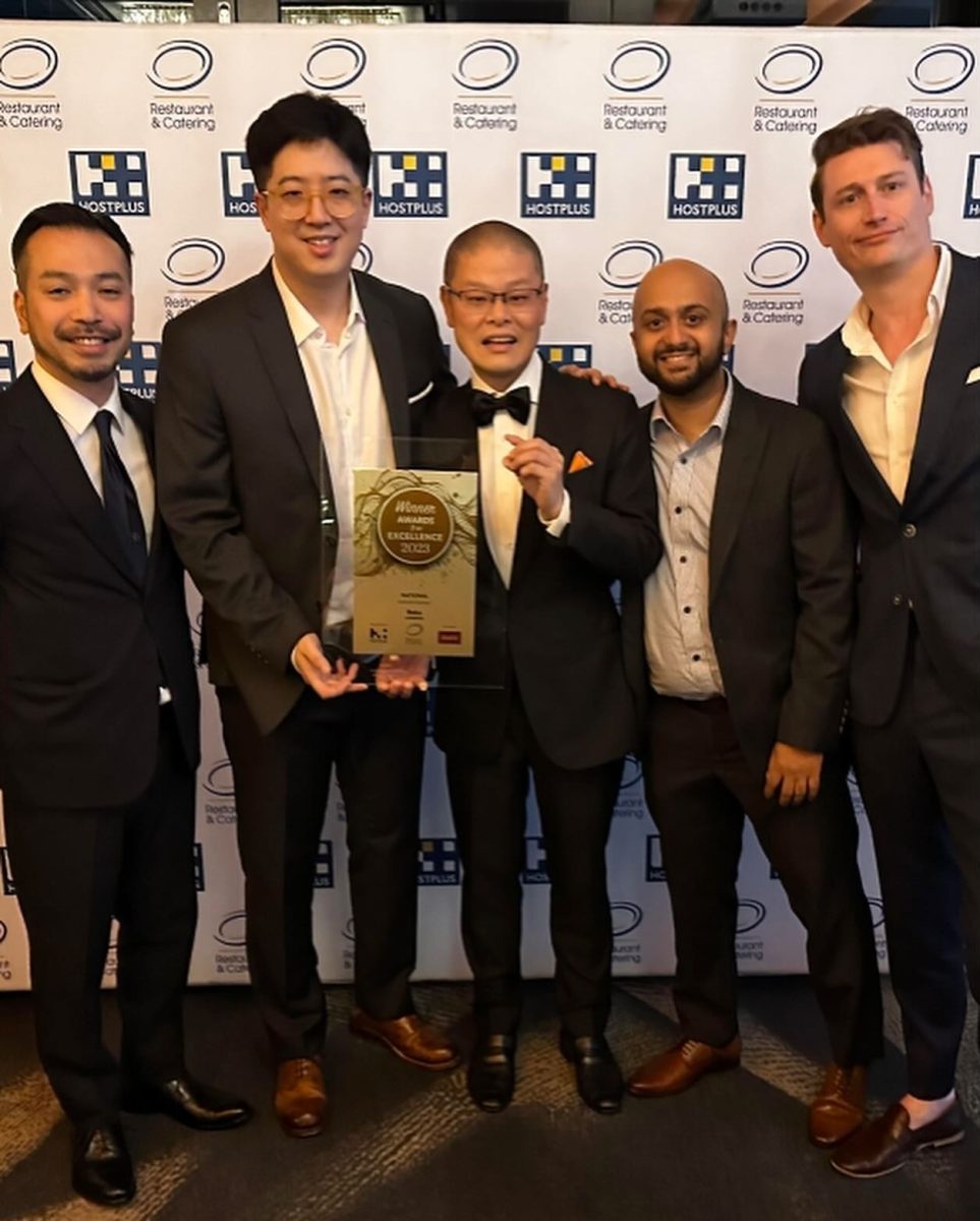 Group of men holding an award in front of branded background