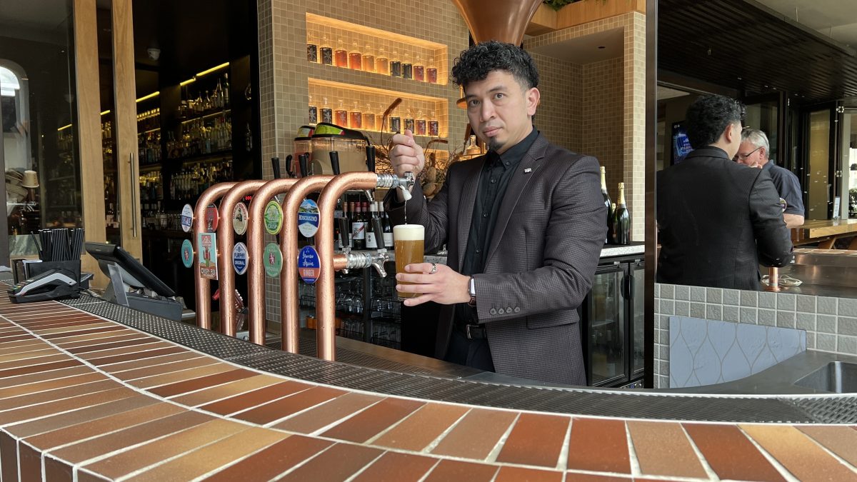 A man in a dark suit pouring a beer