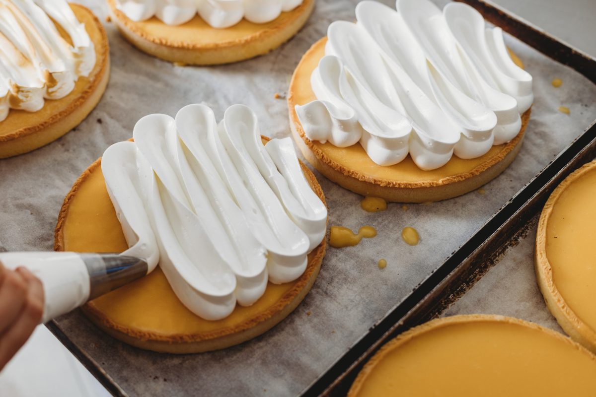 Tarts with meringue being piped onto them