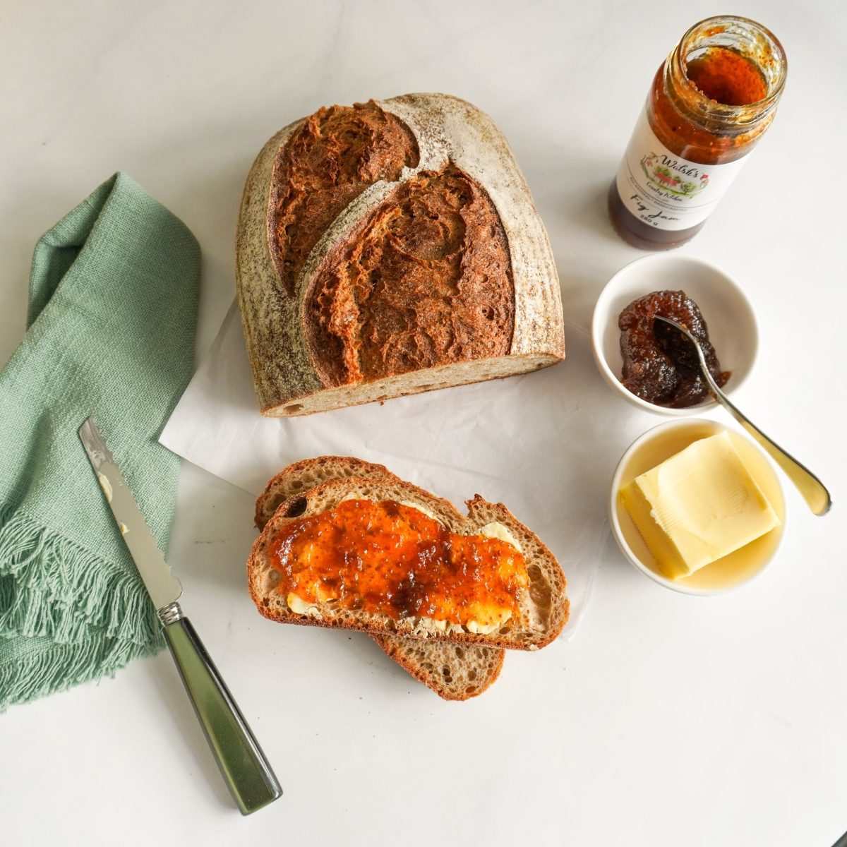 A loaf of bread and condiments, photographed from above