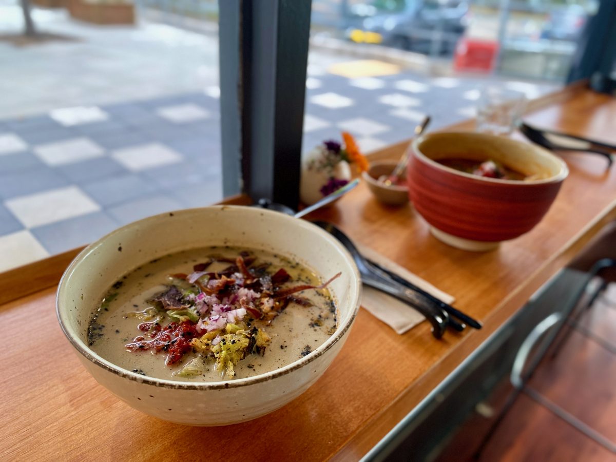 Two bowls of ramen on a bench