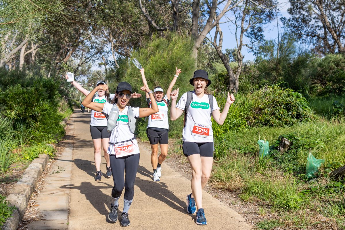 Four hikers wave their arms.