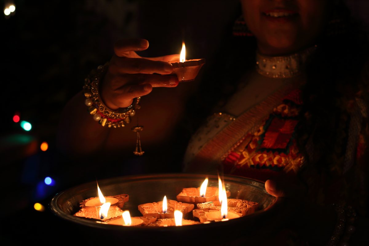 Woman lights floating candles for Diwali