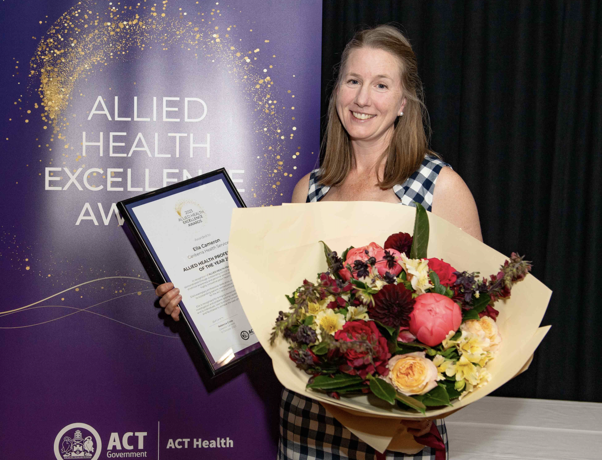 A young woman with a bouquet of flowers and a framed plaque 