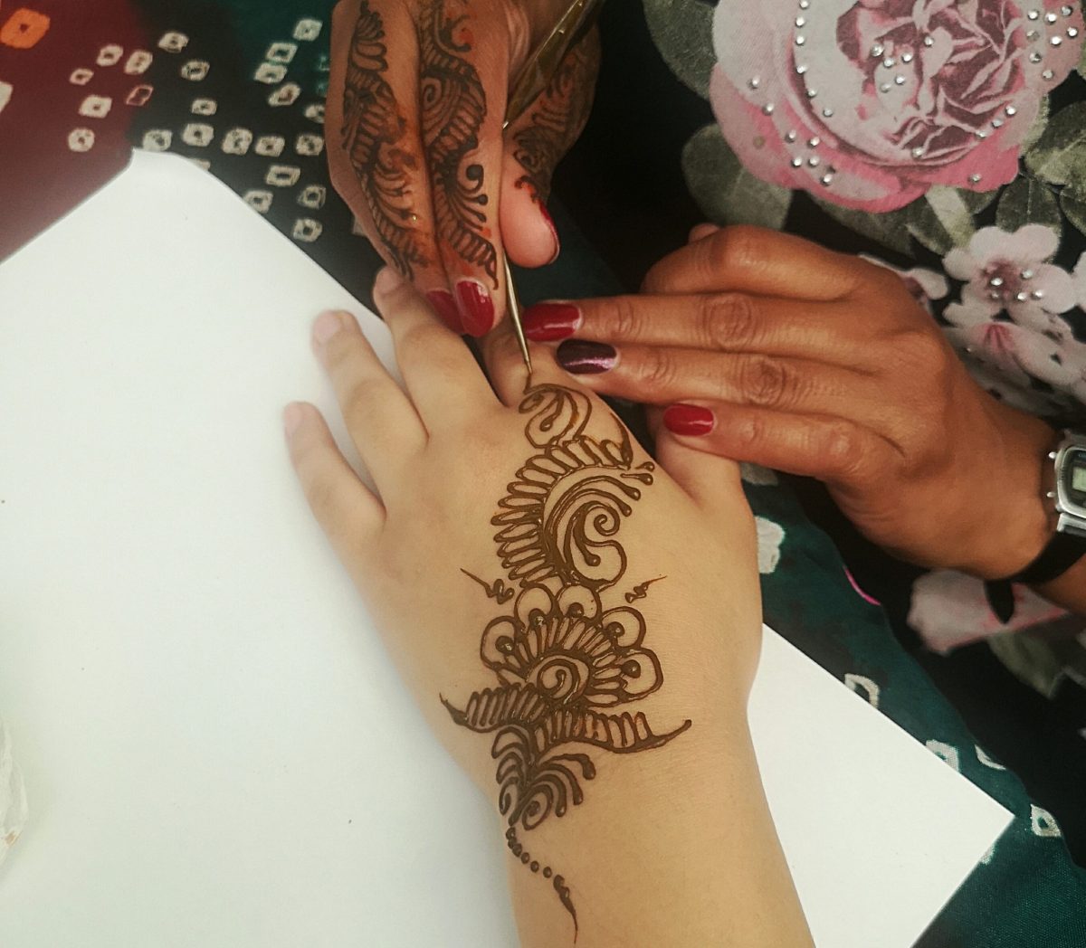 woman doing henna tattoo on a child's hand