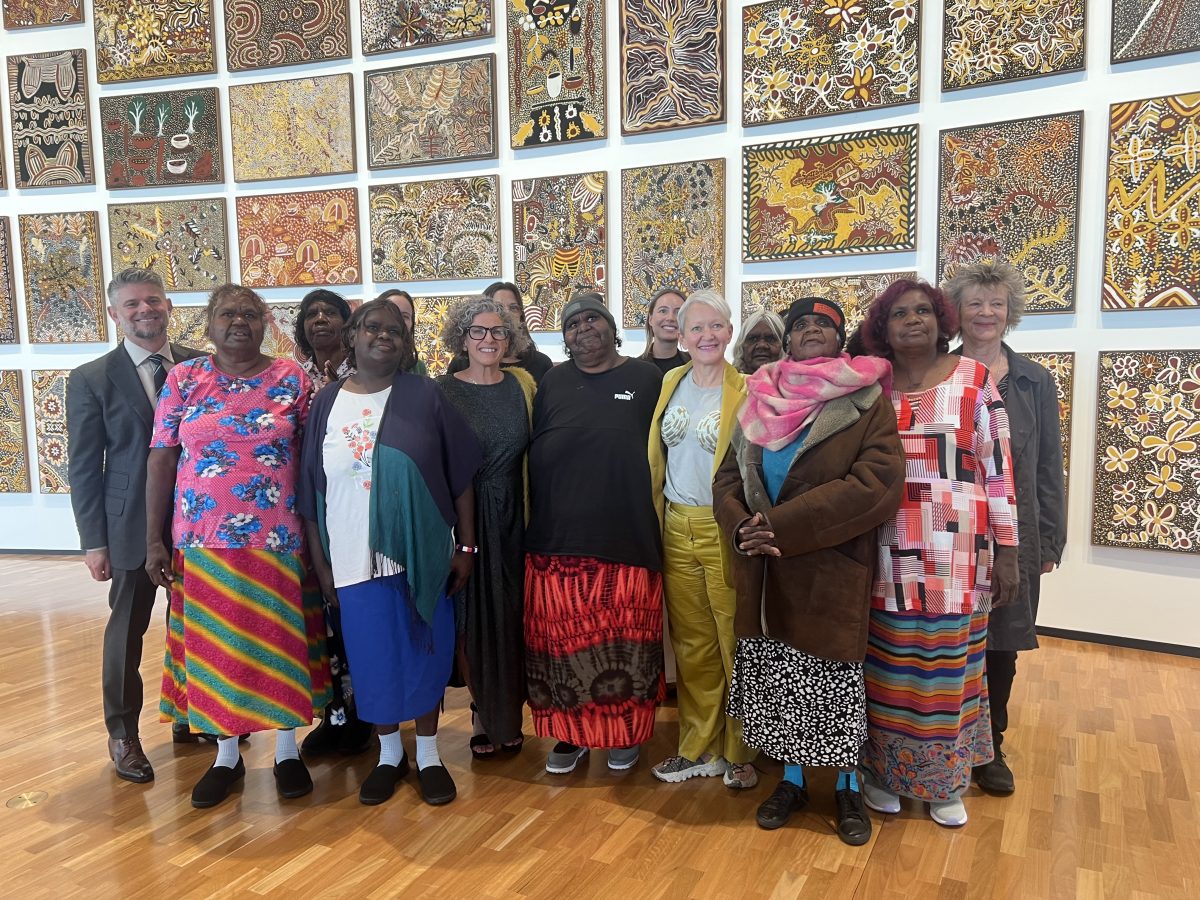 group of Aboriginal women standing in front of many artworks