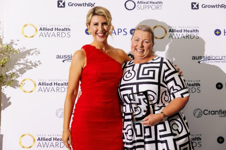 A woman in a red dress with her arm around a woman in a black-and-white dress