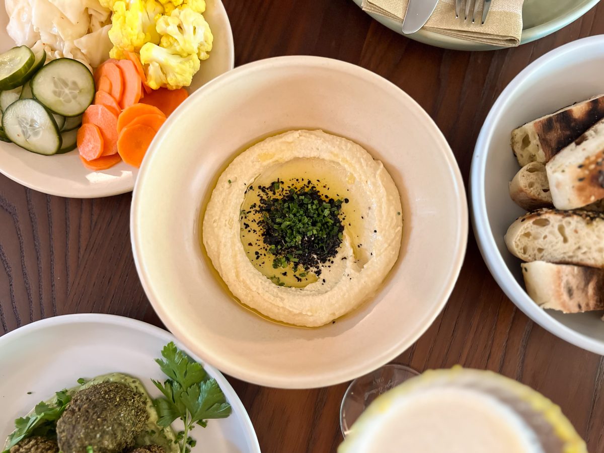 Several plates on a table with a bowl of hummus