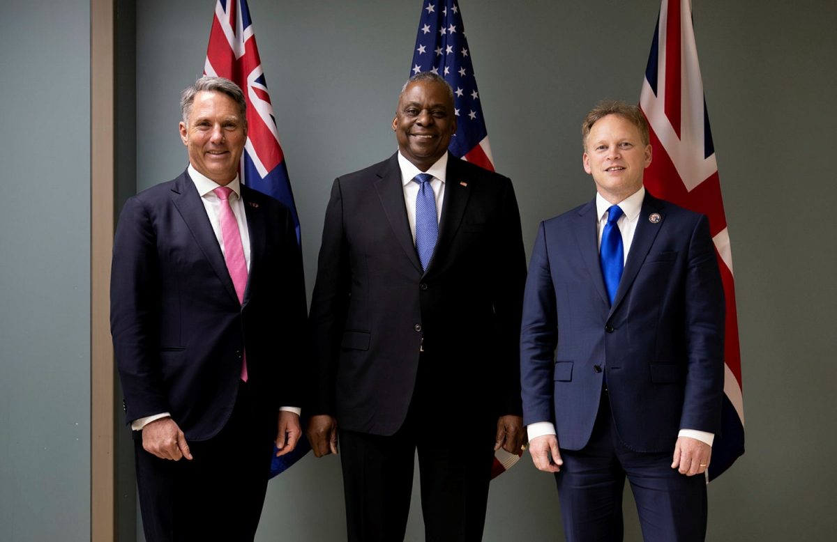 three men standing in front of flags