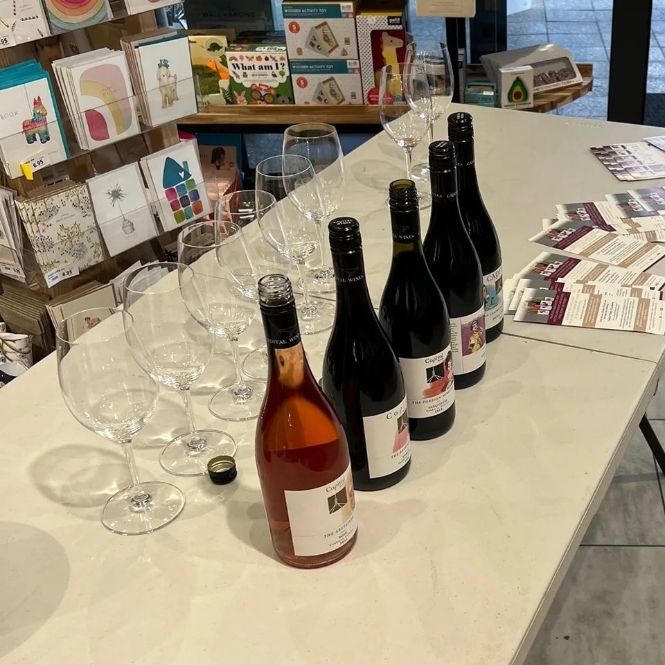 A line of wine bottles with glasses behind them