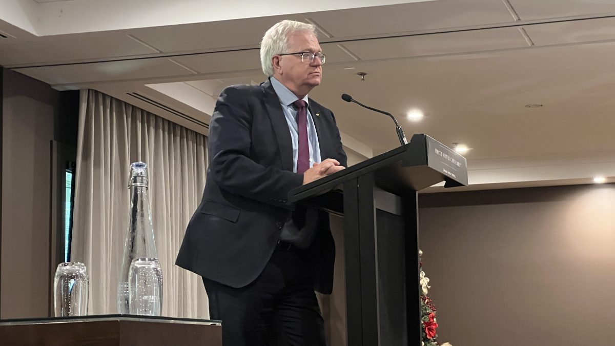 Brian Schmidt speaking from a podium to a seated room at the Hyatt.