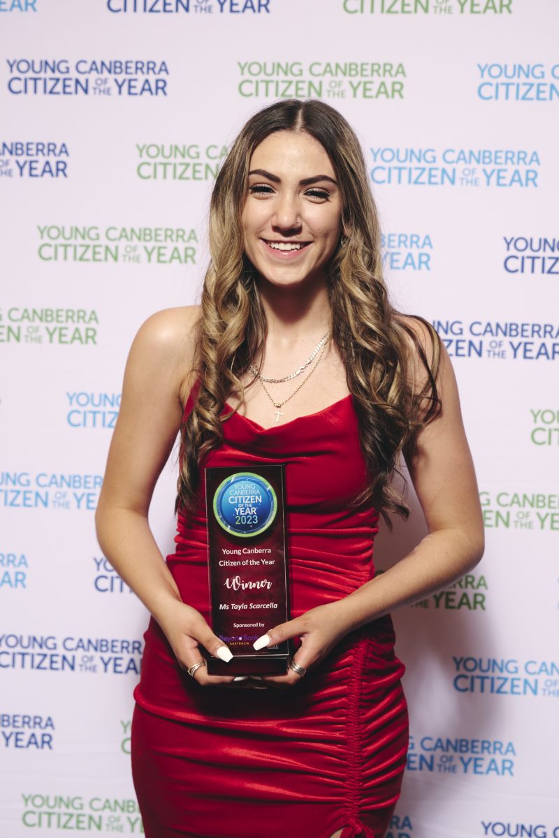 Young woman in red dress holding award.