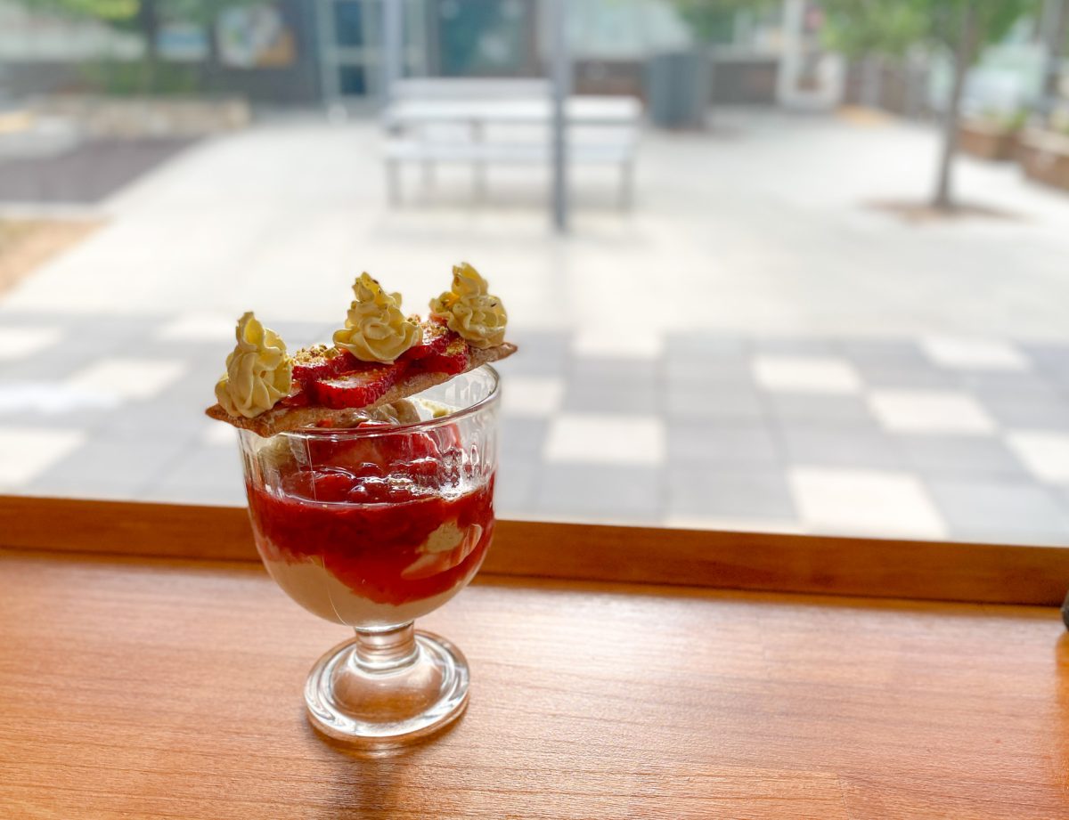 beautiful looking berries and cream in a glass on a bench.