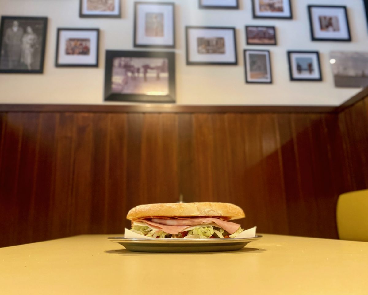 A good looking sandwich with a wall of black and white photos behind.