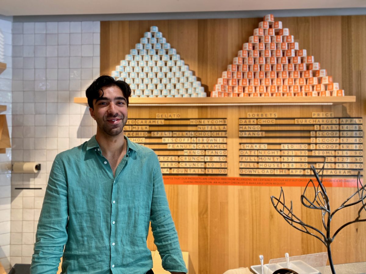 Omer wears a green shirt and stands in front of list of gelato flavours.