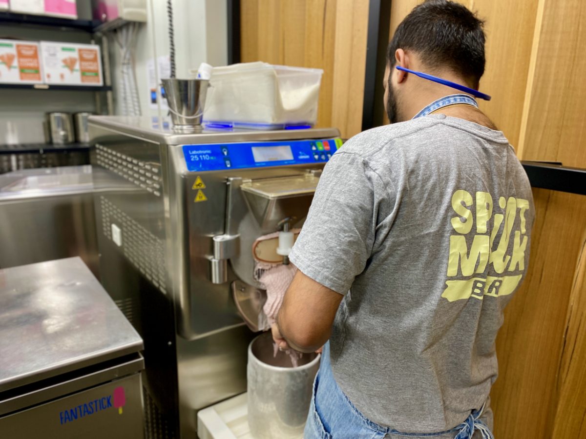 Man in Spilt Milk t-shirt collects freshly churned gelato in a metal tub.