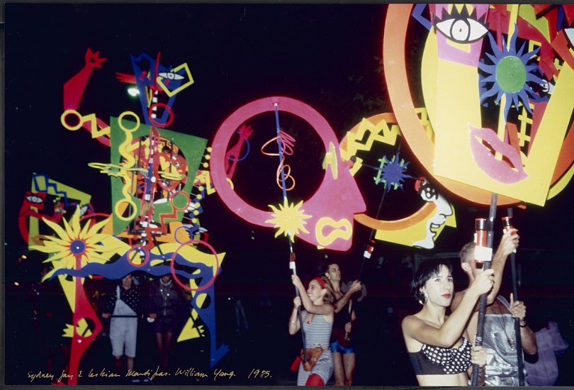 People walking in a parade with abstract colour designs and shapes.